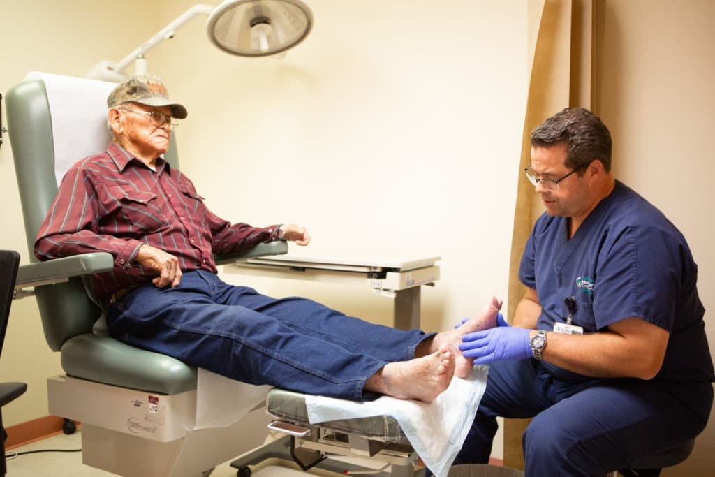 Patient sitting and having his foot examined